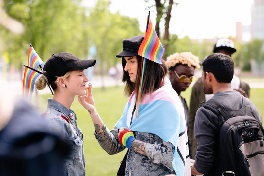 Student placing rainbow sticker on friend's face at gay pride march