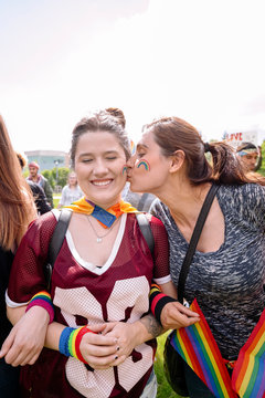 Woman kissing partner on the cheek at gay pride festival