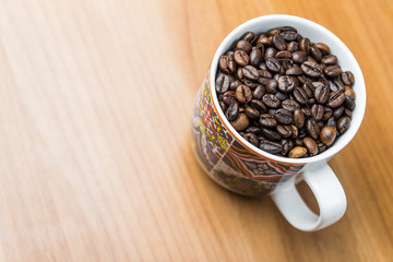 bright close up shot of vintage coffee mug with coffee beans wooden background