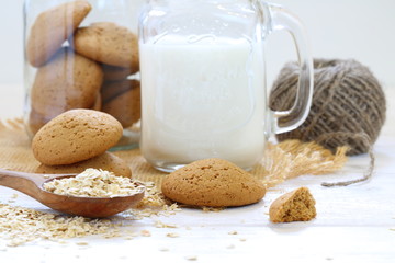 Oatmeal cookies with milk on a white wooden background