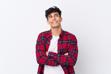 Young Argentinian man over isolated white background looking up while smiling