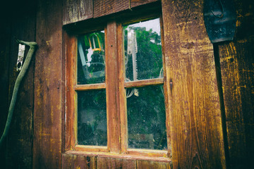 Dirty and dusty window on an old wooden barn, with working tools behind the glass. Close up of old...