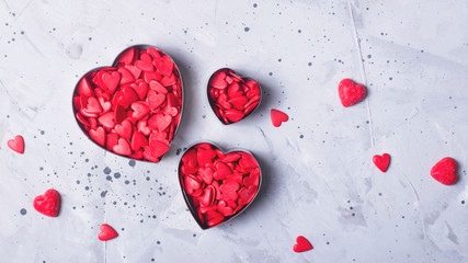 Valentine's day concept. Confectionery powder in the form of red hearts on a gray concrete background.
