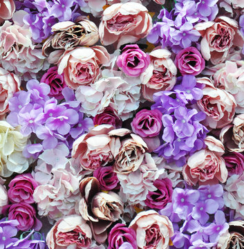 Artificial flowers close up. Romantic background of multicolored artificial roses. Beautiful base for wedding decoration