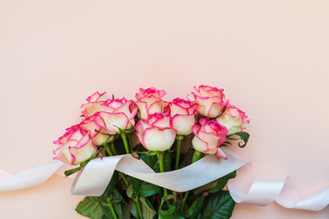 Bouquet of fresh pink roses decorated pink ribbon on pink background. Top view. Flat lay. Copy space. Valentines day, mothers day or birthday celebration concept
