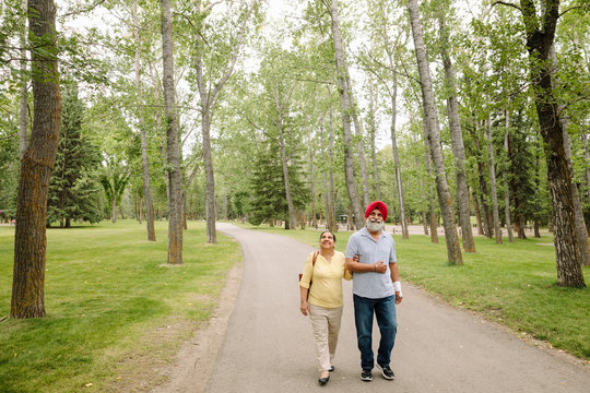 Senior couple walking along path in park