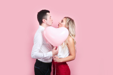 Fototapeta na wymiar Couple covering faces with balloon on pink background