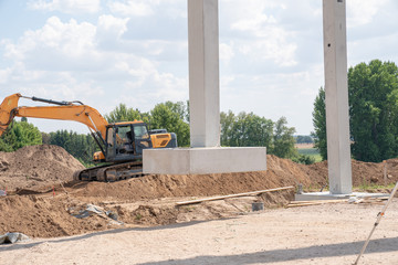 on a construction site, concrete columns for a factory building are placed with the help of a large...
