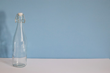 Empty glass bottle on a blue white background