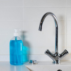 Fragment of the interior of the kitchen. Liquid blue soap in a transparent plastic dispenser is located next to the sink.