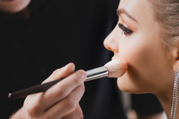 cropped view of Makeup Artist doing makeup to attractive model on backstage