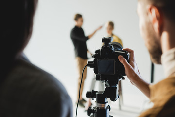 selective focus of producer and photographer taking photo of model and hairstylist on backstage