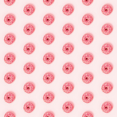 Seamless pattern with donuts in a pink glaze with a white sprinkles on a pink background. Sweets and desserts. This pattern is seamless in horizontal and vertical.