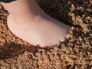 pie de niño en la arena humeda de la playa