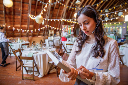 Female wedding planner with clipboard and headset preparing for wedding reception