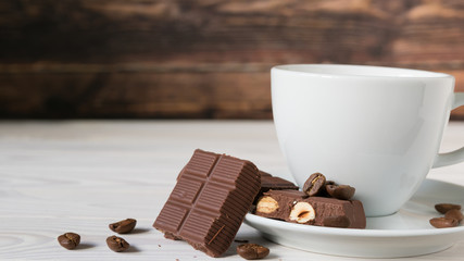 pieces of chocolate with hazelnuts and coffee beans on a brown tablecloth