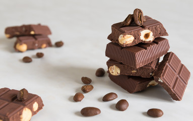 pieces of chocolate with hazelnuts and coffee beans on a marble table