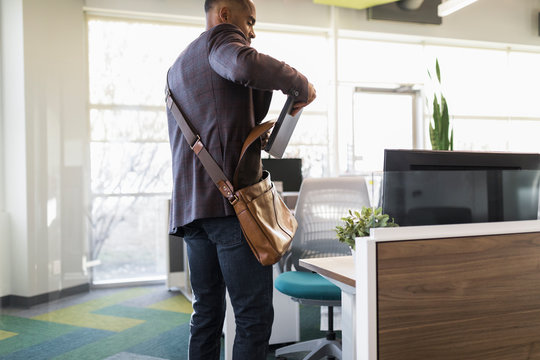 Portrait Of Mature Man Putting Laptop In Shoulder Bag In Modern Office