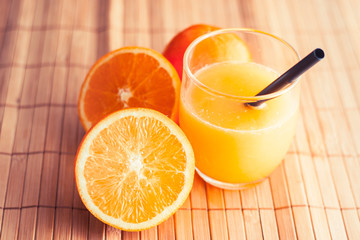 glass of juice and orange on wooden table