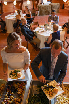 Mature bride and groom at wedding reception buffet line