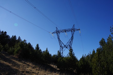Poteau en métal de ligne électrique d'énergie de haute tension en montagne et ciel bleu