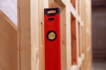 Quality control of the construction of wooden building structures of a frame house. Measurement of vertical deviation of installed structures.