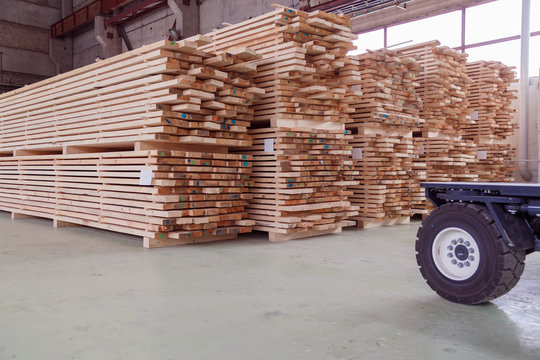 Warehouse or factory for sawing boards on sawmill indoors. Wood timber stack of wooden blanks construction material. Logging Industry.