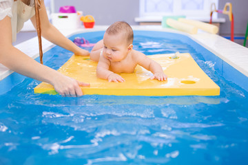 Litle baby in pool swimming bathing during health procedures.