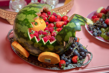 Inside the plate, the raisins, oranges and grapes. A chariot carved with strawberry watermelon in a decorated watermelon.