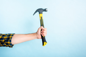 cropped view of workman holding hammer isolated on blue
