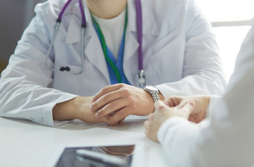 Portrait of a male doctor with laptop sitting at desk in medical office