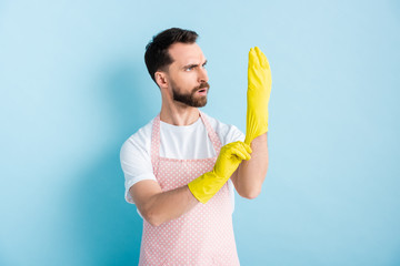 surprised bearded man wearing yellow rubber glove on blue