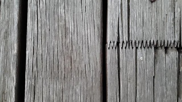 Slow motion slide over old rotting grey wooden floor beams nailed down with interlocking joints  patio flooring.