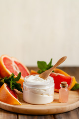 Concept of natural fruity organic ingredients in cosmetology. Extract of grapefruit for moisturizing, delicate skin nutrition, pore narrowing and anti-cellulite effect. Wooden background, copy space