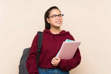 Fototapeta premium Young student Asian girl woman over isolated background laughing and looking up
