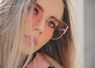 Beautiful stylish blonde woman in pink sunglasses in outdoor.
