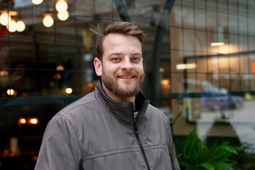 Portrait of a man smiling outside of a cafe downtown in an urban setting