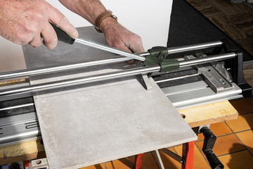 the mason cuts a ceramic tile with a tile cutter