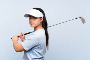 Young golfer Asian girl over isolated blue background