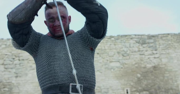 Strong warrior with malice killing enemy with sword at camera