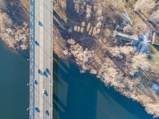 Aerial drone veiw. Kiev Paton Bridge in sunny weather. Cars are driving along the bridge, the shadow from the bridge falls onto the water in the Dnieper River.