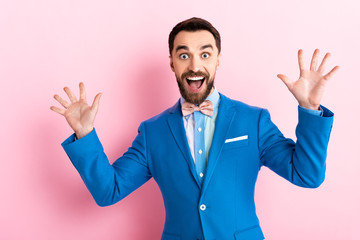 excited bearded businessman with opened mouth gesturing on pink