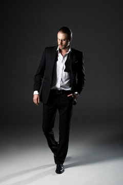 handsome man in elegant black suit on grey