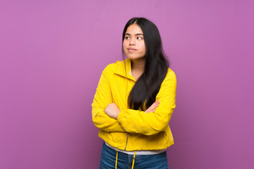 Young teenager Asian girl over isolated purple background making doubts gesture while lifting the shoulders