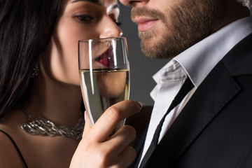 tender couple holding glass of champagne on valentines day, isolated on grey