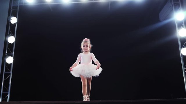 Children's ballet. Little ballerina on stage makes a bow to the audience. Cute baby. Slow motion