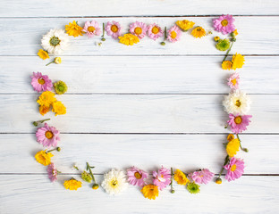 Frame made of colorful flowers on white wooden background. Top view. Valentine's background. Copy space.