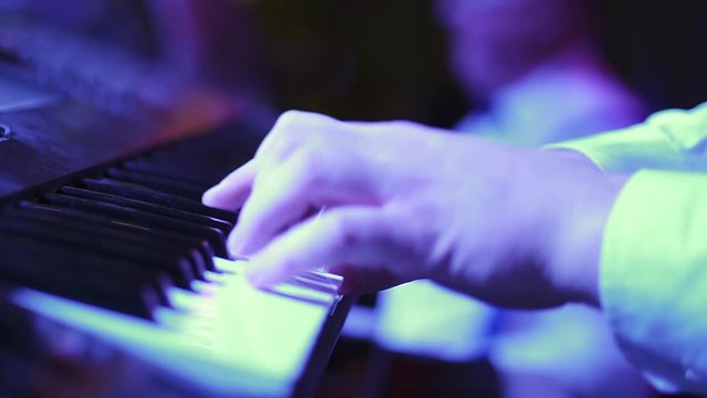 Close up hands of man playing a keyboard instrument. Selective soft focus. Nightlife and entertainment concept