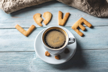 Cup of coffee and a message from a sweet cookie in the form of the word love. Romantic Valentine's day gift