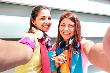 Happy girlfriends taking selfie on break at run training in urban area - Young happy women having fun together with fitness jogging workout - Sport influencer concept promoting energetic drinks